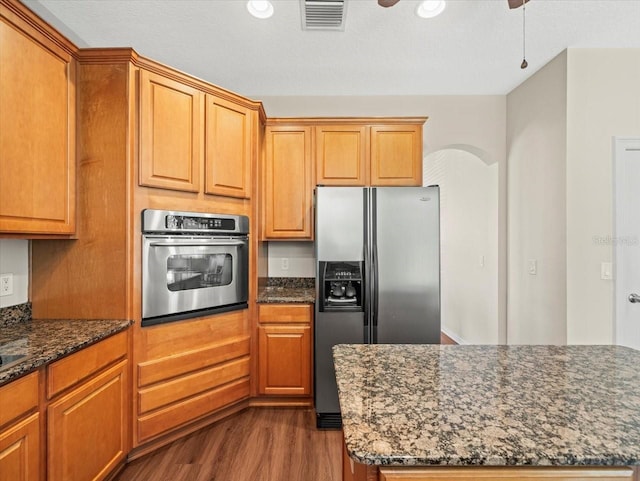 kitchen with dark hardwood / wood-style floors, stainless steel appliances, dark stone counters, and a textured ceiling