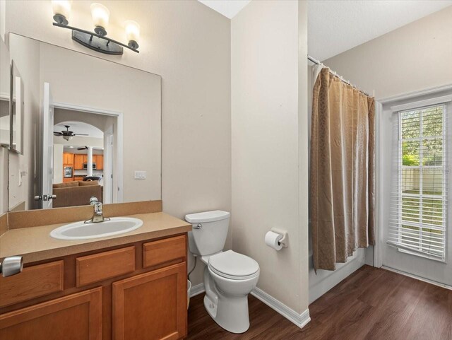 bathroom with hardwood / wood-style floors, toilet, ceiling fan, a shower with curtain, and vanity