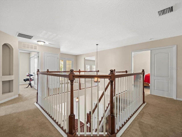 hallway featuring light carpet and a textured ceiling