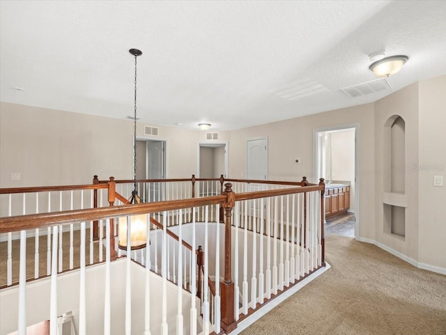 hall with a textured ceiling and carpet flooring