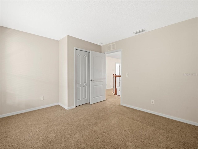 unfurnished bedroom with a closet, light carpet, and a textured ceiling