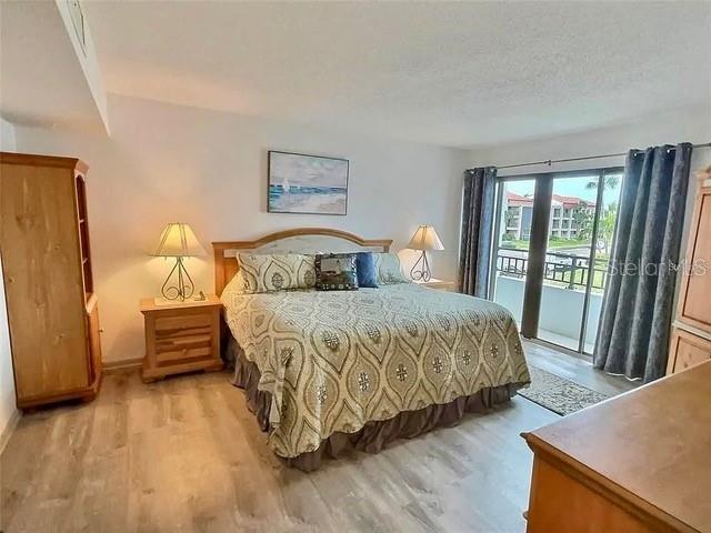 bedroom featuring a textured ceiling, light wood-type flooring, and access to outside