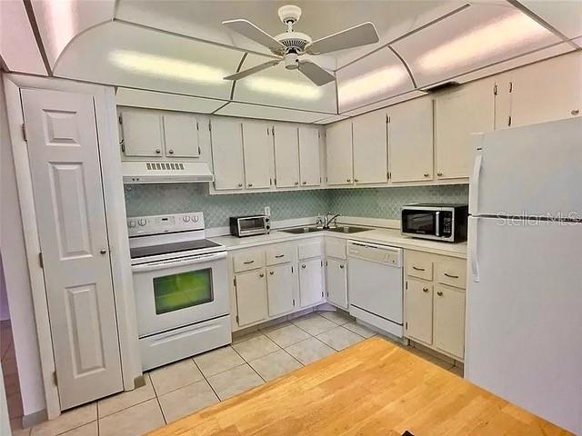 kitchen featuring light tile patterned floors, white appliances, ceiling fan, and sink