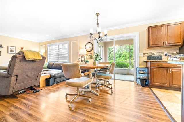 dining space featuring crown molding, an inviting chandelier, and light hardwood / wood-style floors