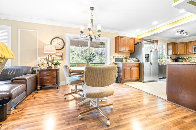 dining room with crown molding, light hardwood / wood-style floors, and a notable chandelier