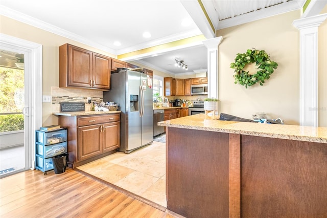 kitchen featuring backsplash, plenty of natural light, stainless steel appliances, and ornate columns