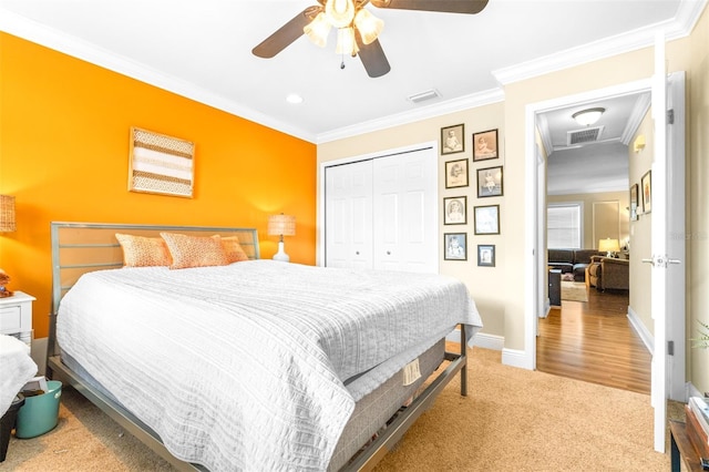 bedroom featuring light carpet, ornamental molding, a closet, and ceiling fan