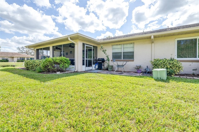 back of property featuring ceiling fan, a sunroom, and a lawn