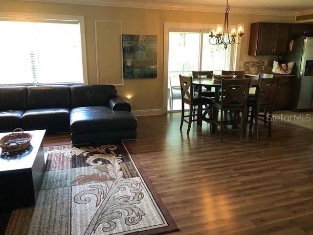 living area featuring a chandelier, ornamental molding, and wood finished floors