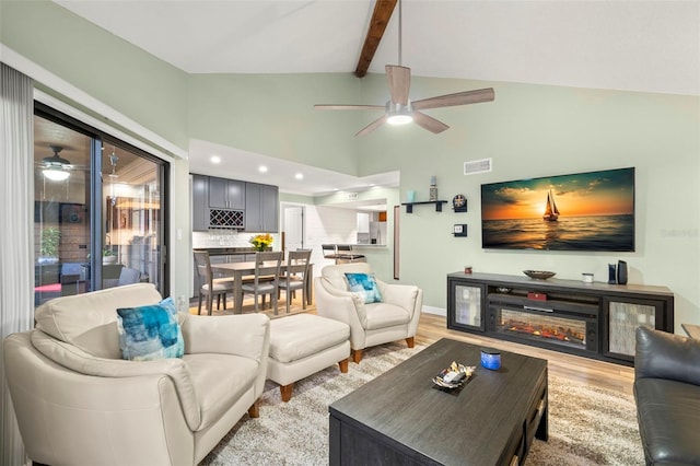 living room with vaulted ceiling with beams, ceiling fan, and light hardwood / wood-style flooring