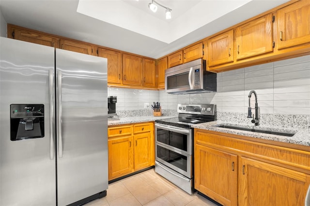 kitchen with light stone countertops, sink, stainless steel appliances, decorative backsplash, and light tile patterned floors