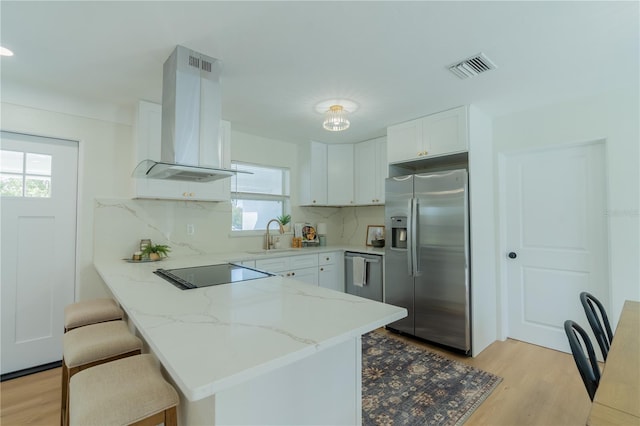 kitchen featuring kitchen peninsula, backsplash, extractor fan, white cabinetry, and stainless steel appliances