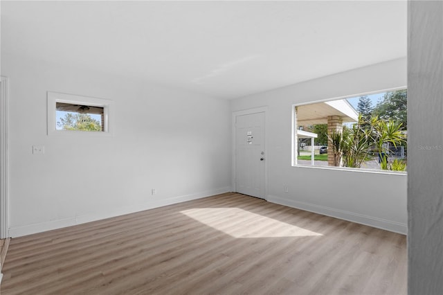 unfurnished room with plenty of natural light, a skylight, and light hardwood / wood-style flooring