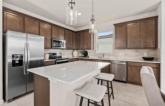 kitchen featuring light stone countertops, tasteful backsplash, appliances with stainless steel finishes, and a kitchen island