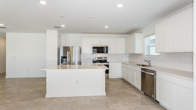 kitchen featuring stainless steel appliances, a center island, sink, and white cabinets