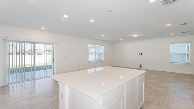 kitchen featuring white cabinetry, a center island, a wealth of natural light, and light tile patterned floors