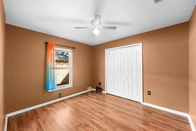 unfurnished bedroom with light hardwood / wood-style flooring, a closet, and ceiling fan