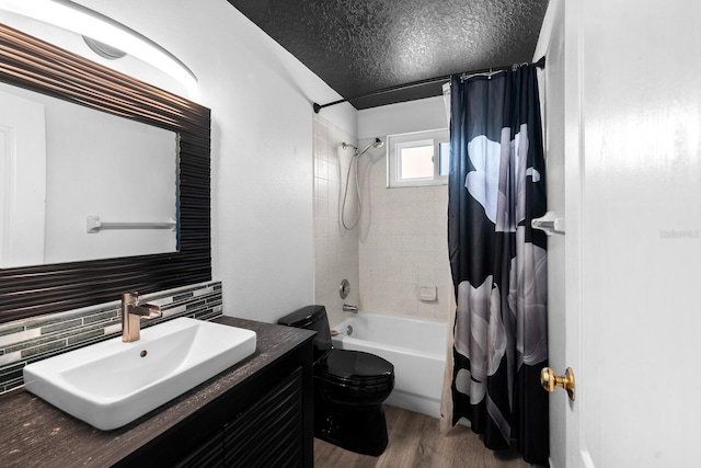 full bathroom with toilet, a textured ceiling, vanity, shower / bath combo with shower curtain, and hardwood / wood-style floors