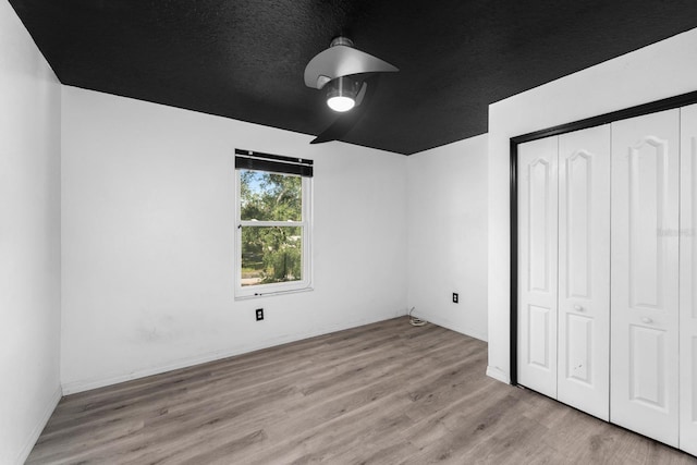 unfurnished bedroom with ceiling fan, a textured ceiling, light wood-type flooring, and a closet