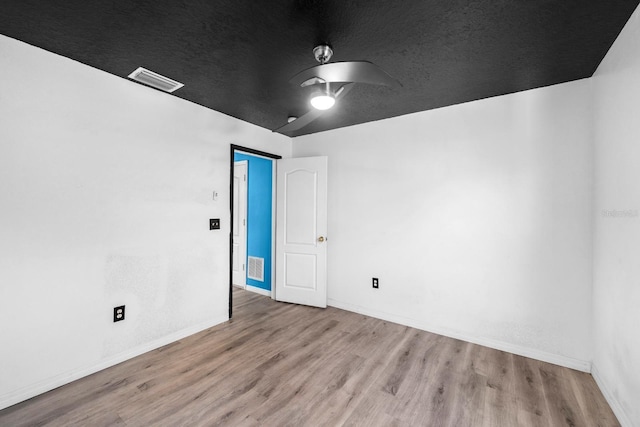 empty room with ceiling fan, light hardwood / wood-style flooring, and a textured ceiling