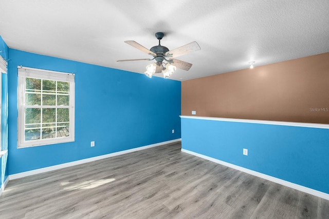 empty room featuring a textured ceiling, wood-type flooring, and ceiling fan