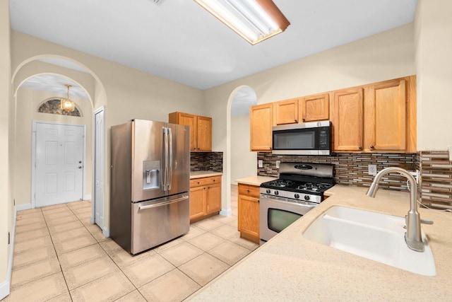 kitchen with sink, backsplash, stainless steel appliances, and light tile patterned floors