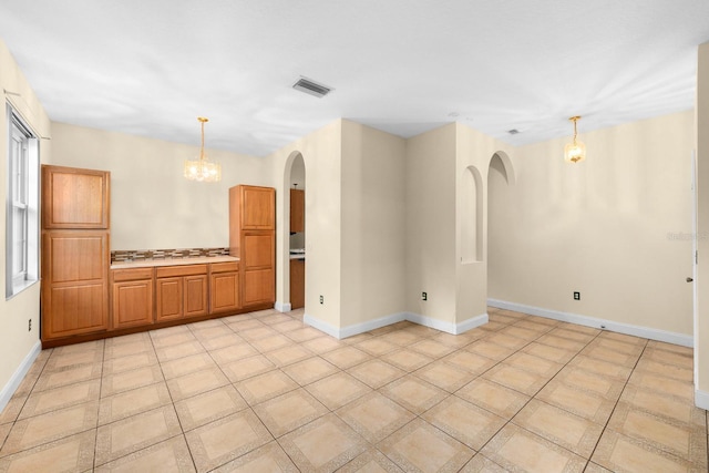 tiled empty room featuring a chandelier