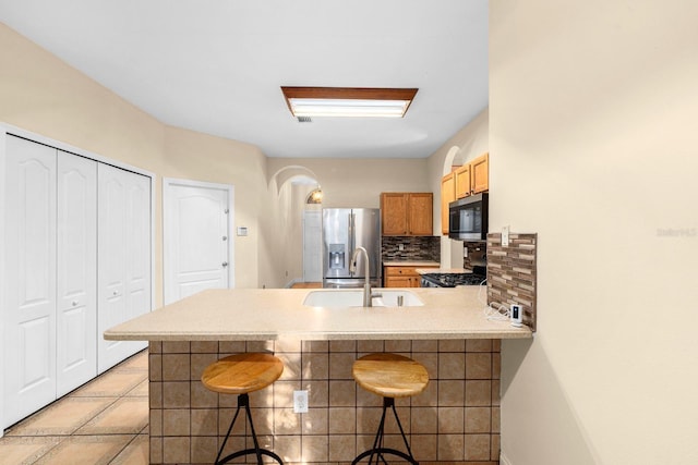 kitchen with a breakfast bar, stainless steel fridge with ice dispenser, and kitchen peninsula