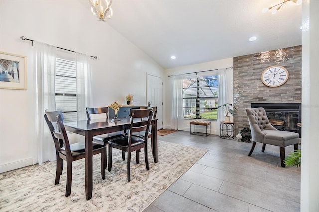 dining space with light tile patterned floors, a large fireplace, high vaulted ceiling, and a notable chandelier