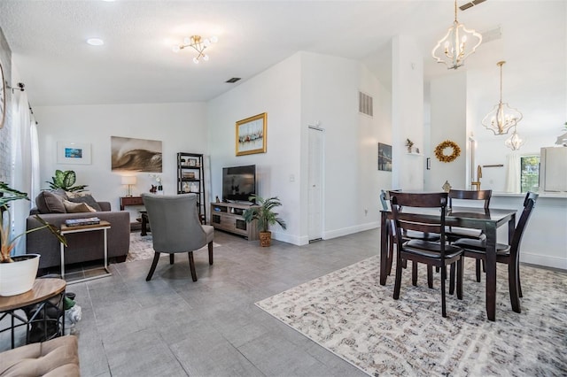 dining area featuring a textured ceiling, lofted ceiling, and a notable chandelier