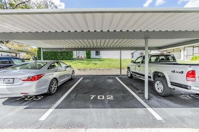 view of parking / parking lot featuring a carport and a lawn