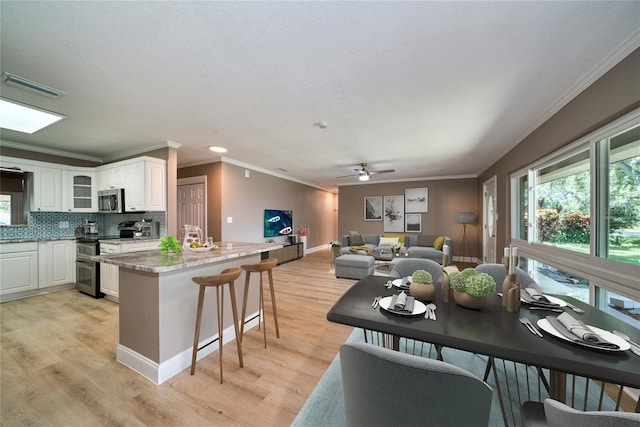 kitchen featuring light hardwood / wood-style flooring, stainless steel appliances, white cabinetry, light stone counters, and ceiling fan