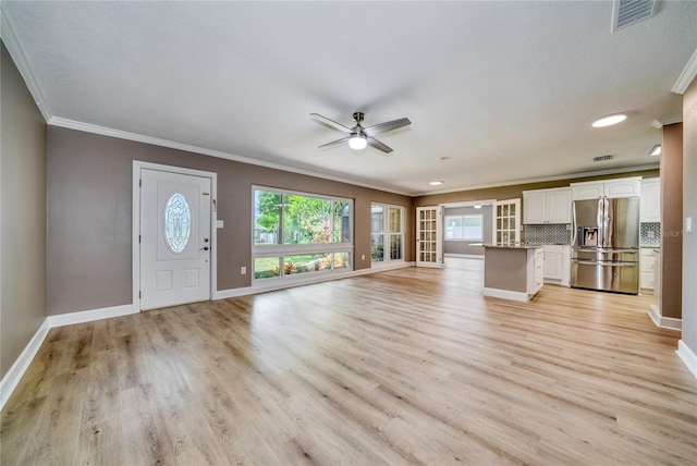 unfurnished living room with ornamental molding, a textured ceiling, light wood-type flooring, and ceiling fan