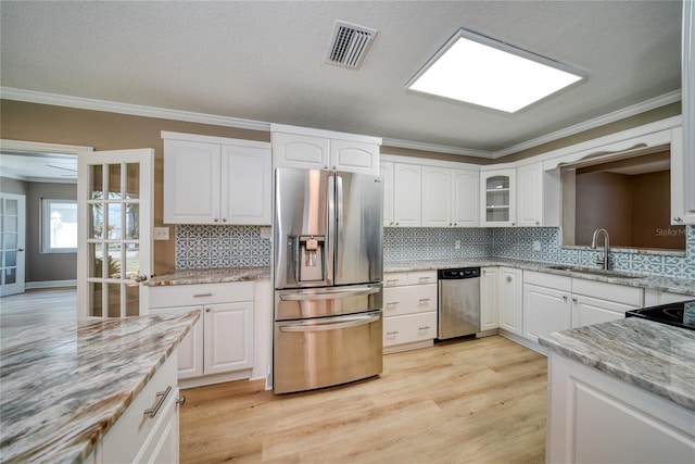 kitchen with sink, appliances with stainless steel finishes, light stone counters, and white cabinetry