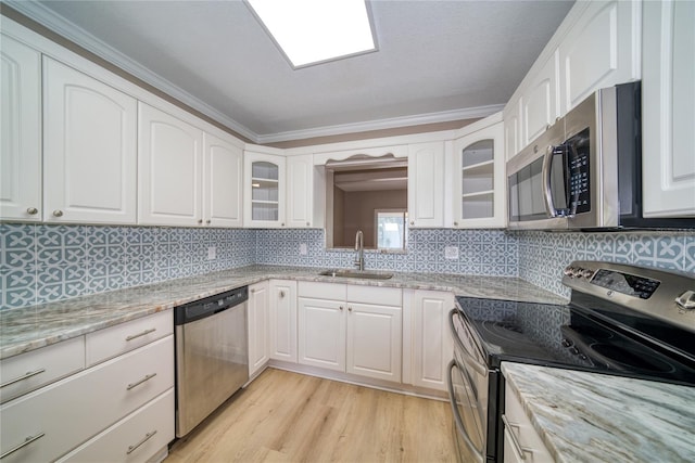 kitchen with sink, appliances with stainless steel finishes, white cabinetry, and light hardwood / wood-style floors