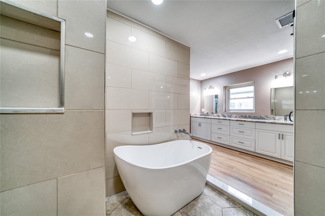 bathroom with vanity, tile walls, hardwood / wood-style flooring, and a washtub