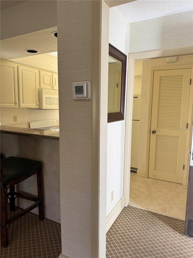 hallway with a textured ceiling and carpet flooring