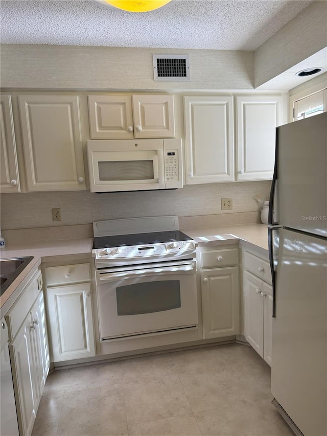 kitchen featuring white appliances, a textured ceiling, sink, and white cabinetry