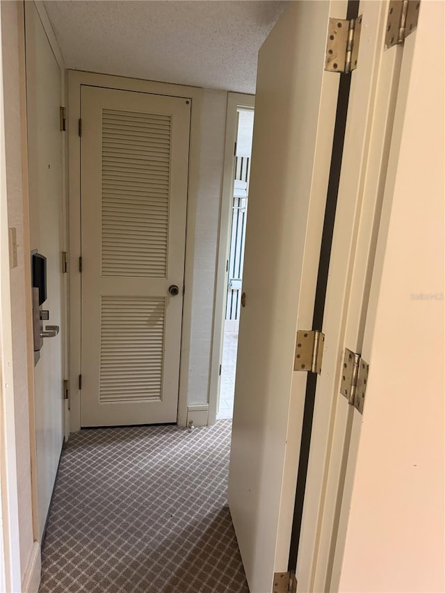 corridor with a textured ceiling and carpet floors