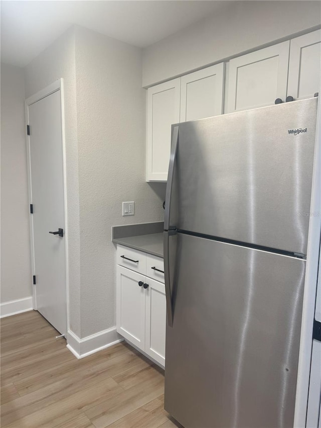 kitchen with white cabinetry, stainless steel fridge, and light wood-type flooring