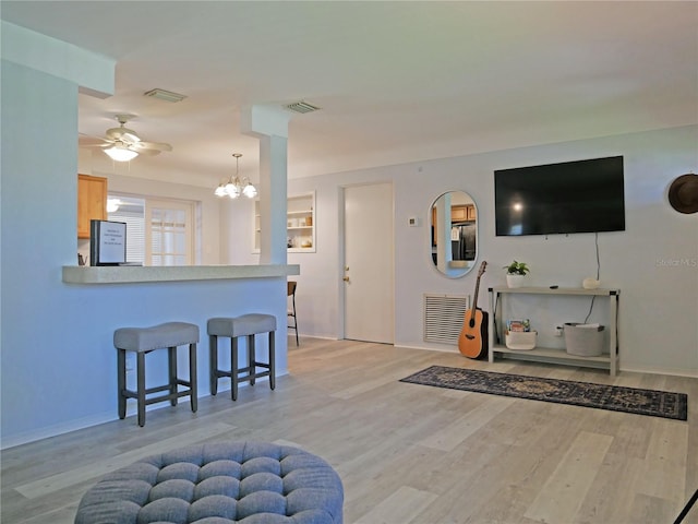 living room featuring light hardwood / wood-style floors and ceiling fan with notable chandelier