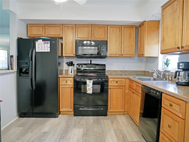 kitchen with black appliances, sink, and light hardwood / wood-style floors