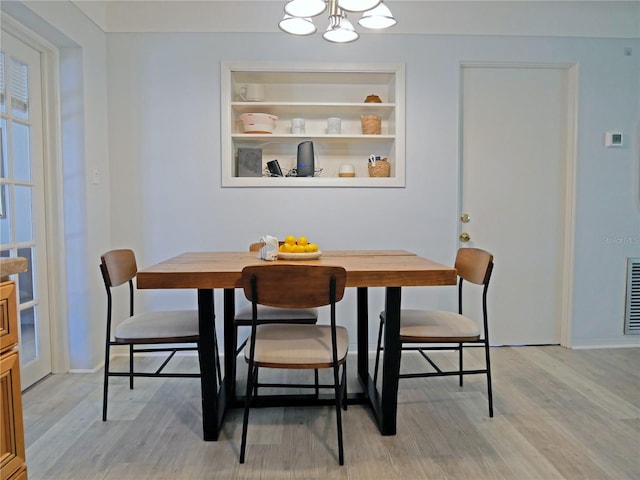 dining room with light hardwood / wood-style floors and an inviting chandelier