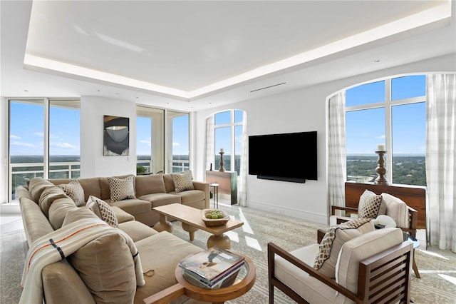 living room with a raised ceiling, carpet flooring, and plenty of natural light