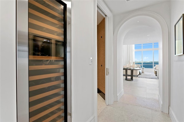 hall featuring a water view, light tile patterned floors, and beverage cooler