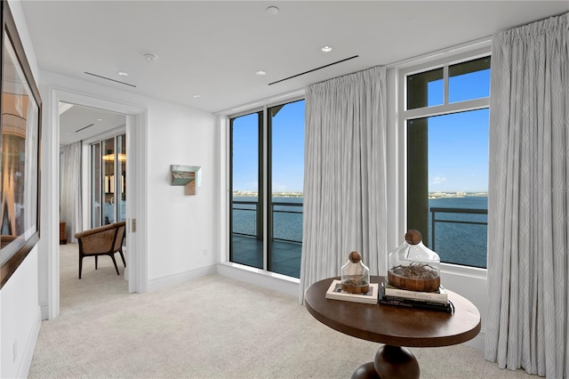 living area with a water view, plenty of natural light, and light colored carpet