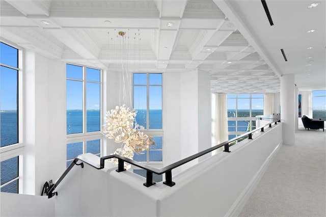 hallway featuring a water view, carpet floors, and a healthy amount of sunlight