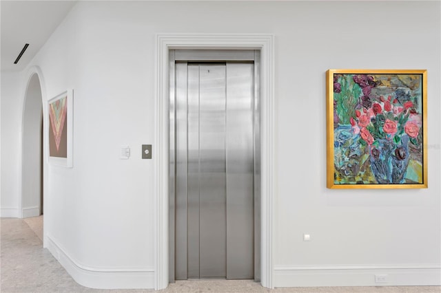 hallway with light carpet and elevator