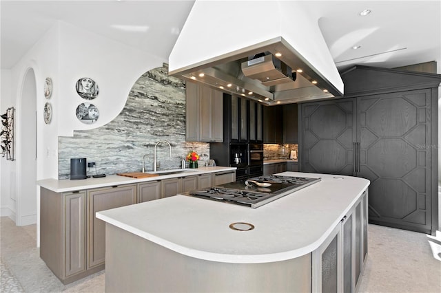 kitchen with decorative backsplash, island exhaust hood, a kitchen island, stainless steel gas stovetop, and sink