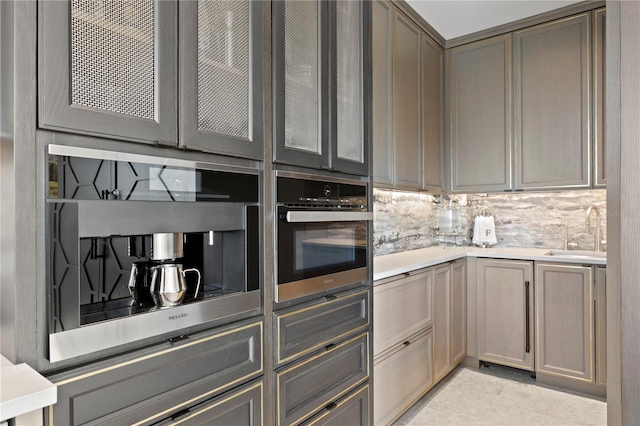 kitchen with sink, gray cabinetry, tasteful backsplash, and oven